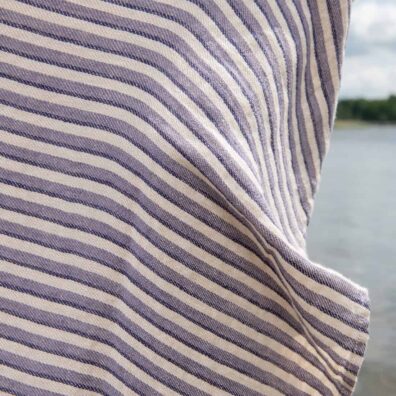 Lininis paplūdimio rankšluostis violetiniais ir tamsiai mėlynais dryžiais smėlio spalvos fone